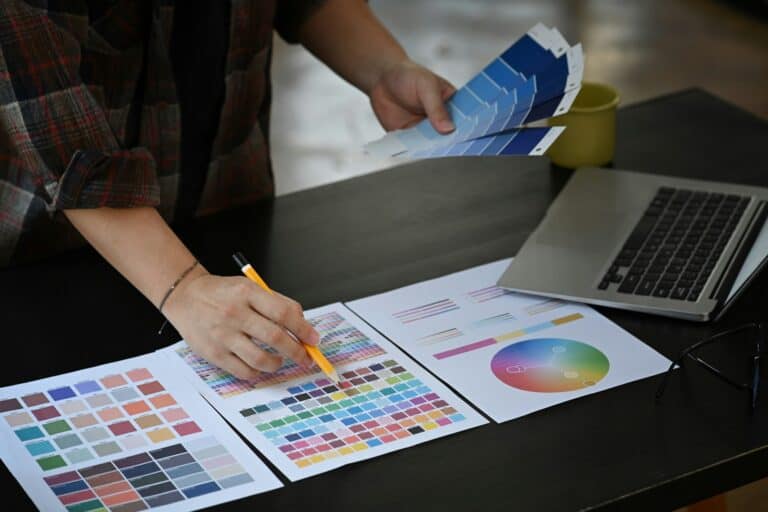 Graphic designer working with color swatches on office desk.