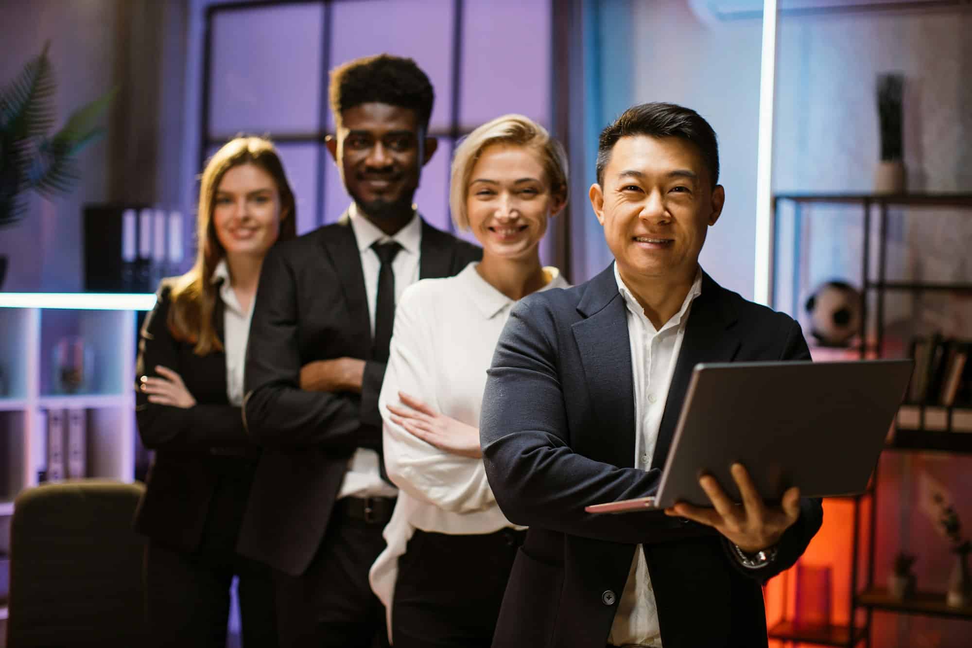 Multiethnic happy company workers standing in a row in creative office, posing on camera